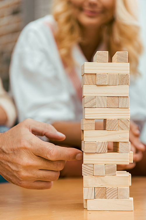 cropped shot of mature people playing with wooden blocks on table at home