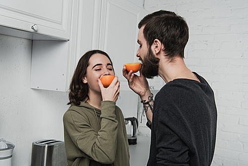 beautiful young couple eating oranges in kitchen