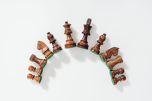 top view of semicircle made of brown wooden chess figures on white background