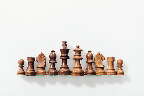 top view of row made of brown wooden chess figures on white background