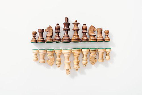 top view of rows made of brown and beige wooden chess figures on white background