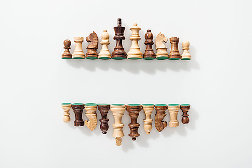 top view of rows made of wooden chess figures on white background with copy space