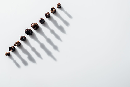 top view of brown chess figures with shadows on white background with copy space