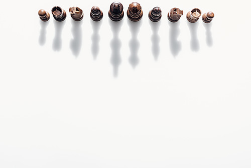 top view of brown chess figures with shadows on white background