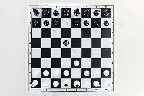 top view of black and white chessboard with figures on white background