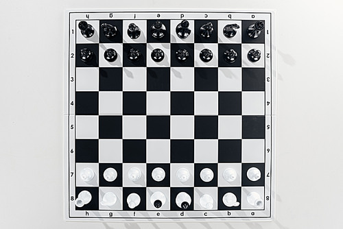 top view of black and white chessboard with chess figures on white background