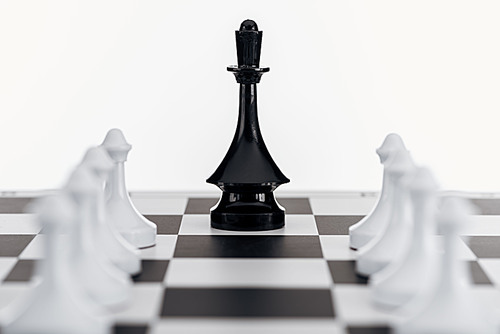 selective focus of chessboard with black queen figure among white pawns isolated on white