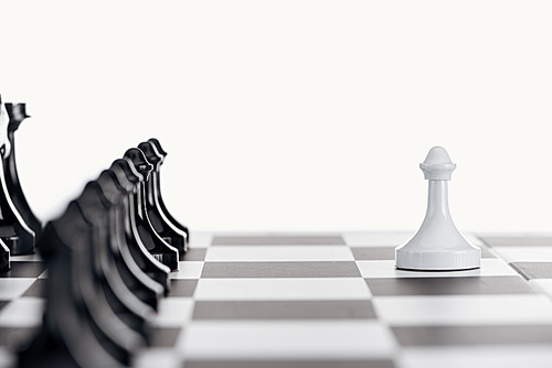 selective focus of chessboard with black chess pieces and white pawn in front isolated on white