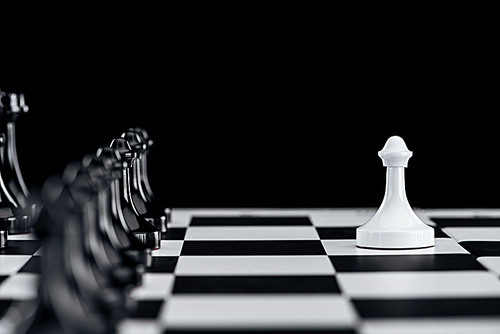 selective focus of chessboard with black chess figures and white pawn in front isolated on black