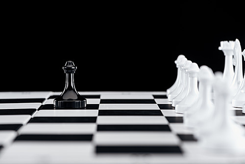 selective focus of chessboard with white chess figures and black pawn in front isolated on black