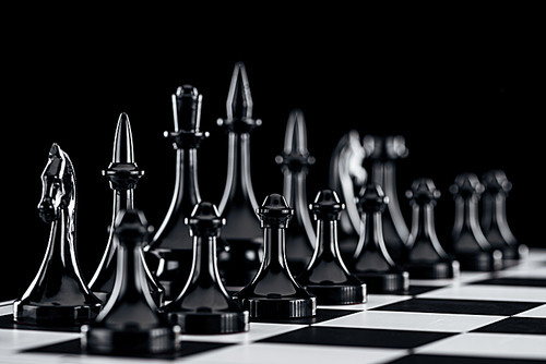 selective focus of chessboard with black chess figures isolated on black