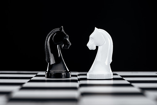 selective focus of chessboard with white and black knights isolated on black