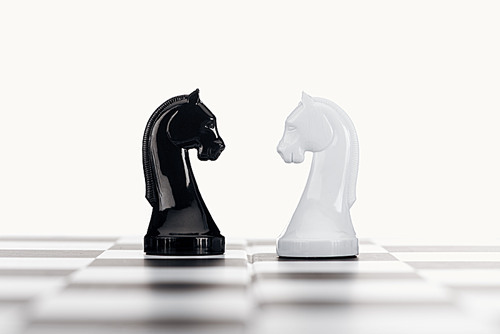 selective focus of chessboard and white and black knights isolated on white