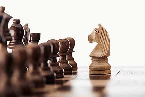 selective focus of wooden chessboard with chess figures and knight in front isolated on white