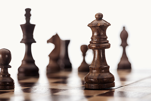 selective focus of wooden chessboard with dark brown chess figures isolated on white