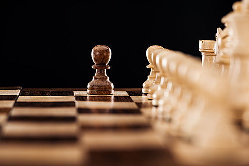 selective focus of wooden chessboard with chess figures and pawn in front isolated on black