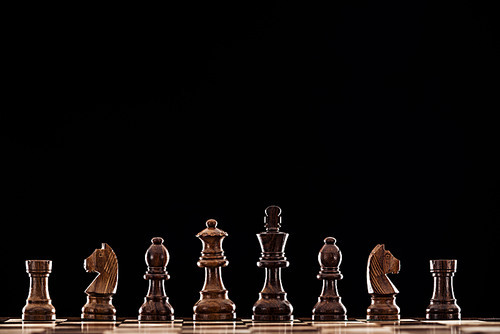 wooden chessboard with brown chess pieces isolated on black