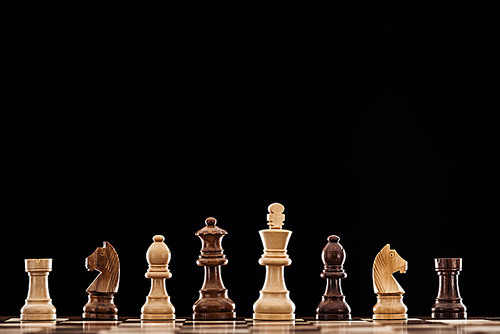 wooden chessboard with brown and beige chess pieces isolated on black