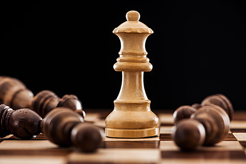 close up of chessboard with scattered wooden figures and queen isolated on black