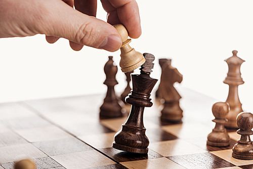 partial view of man holding pawn above wooden chessboard isolated on white