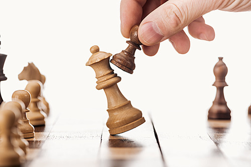 partial view of man doing move with brown pawn on chessboard isolated on white