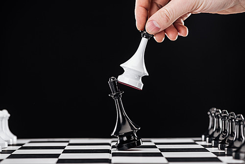 cropped view of man doing move with queen on chessboard isolated on black