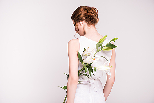 back view of young woman in white dress holding beautiful lily flowers isolated on grey