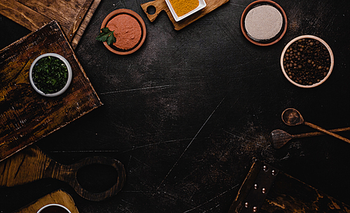 top view of wooden cutting boards and spices on black surface