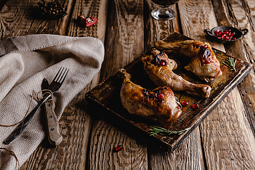 close-up shot of delicious grilled chicken legs on wooden board with cutlery