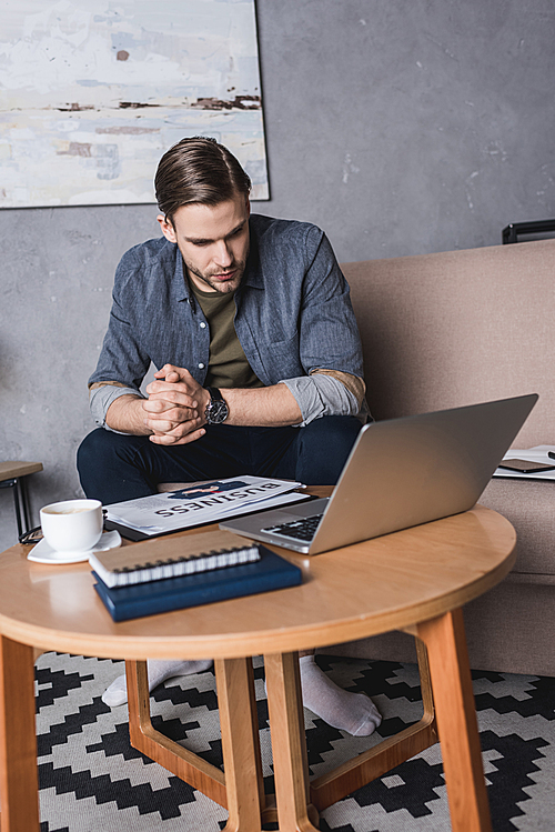 young businessman looking at laptop while sitting on couch