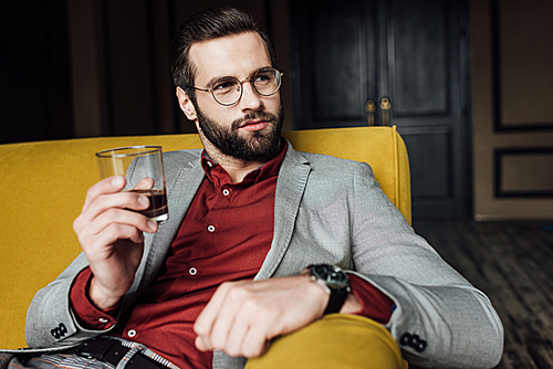 stylish bearded man holding glass of whiskey