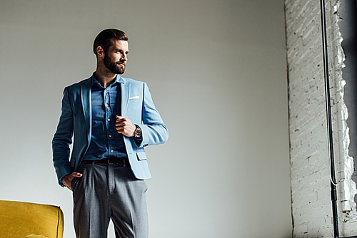 elegant handsome man in blue trendy suit looking at window
