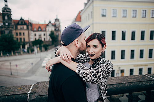 handsome man kissing beautiful young woman  while standing together on bridge in Dresden, Germany