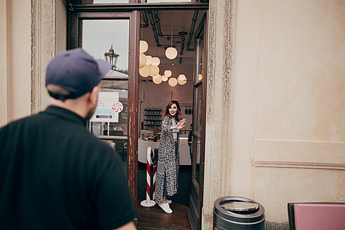 back view of young man looking at beautiful girlfriend standing inside cafe in Dresden