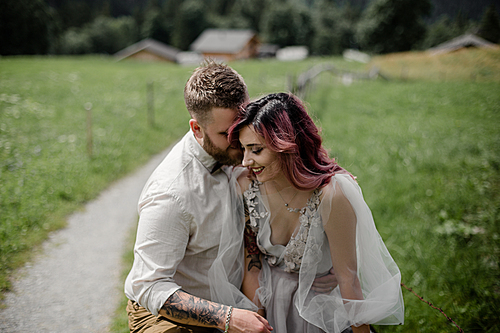 beautiful young bride and groom hugging and laughing in mountain valley, Alps
