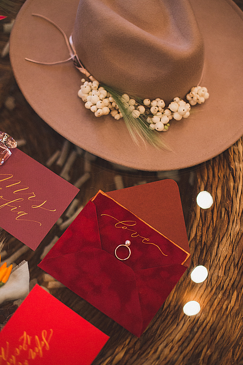 top view of wedding ring, invitations and hat in bohemian style