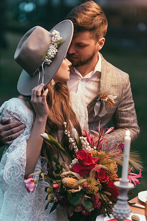 beautiful couple hugging and holding wedding bouquet