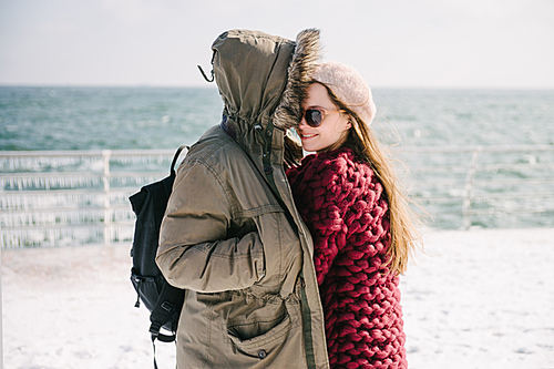 young couple hugging on quay at winter