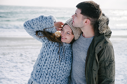 happy young couple hugging on winter seashore