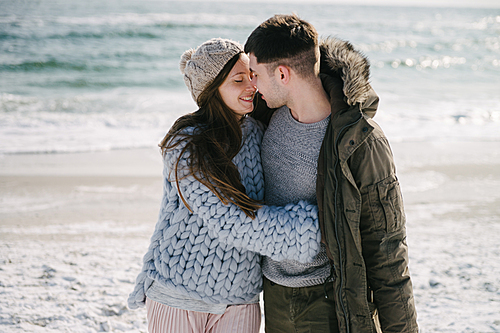 beautiful happy couple embracing on winter sea shore