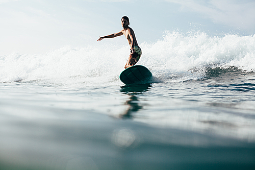 handsome man riding waves on surfboard while having vacation