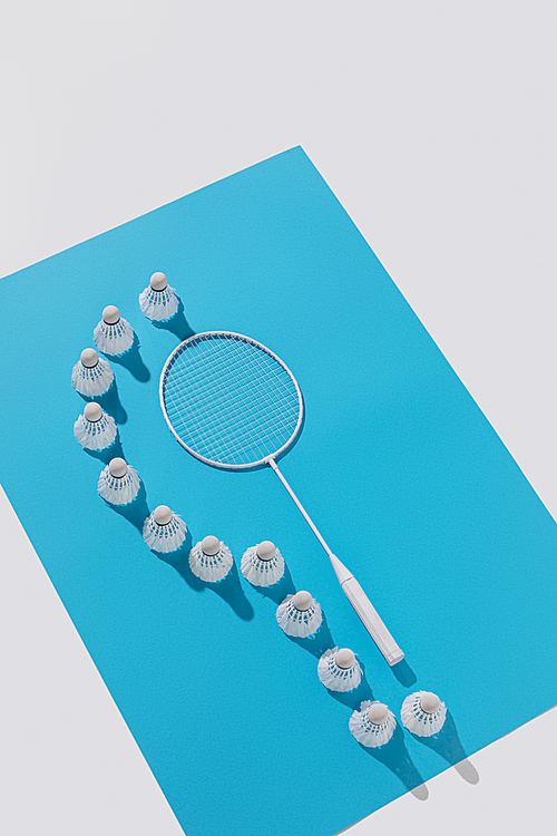 high angle view of badminton racket and shuttlecocks on blue paper, isolated on white