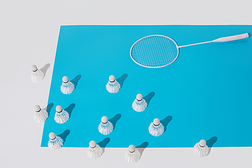 high angle view of white badminton racket and shuttlecocks on blue paper