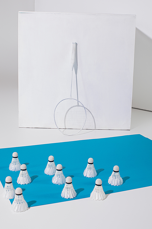 badminton racket at white cube and shuttlecocks on blue paper