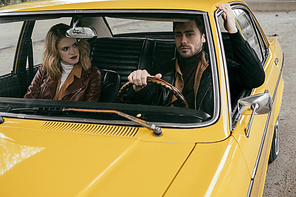 view through the windshield of young couple in leather jackets sitting together in yellow classic car