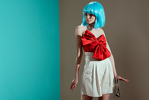 attractive young female model in blue wig and red bow looking away in studio