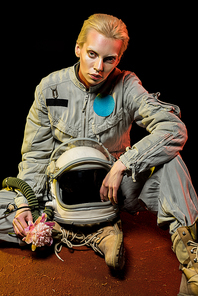 beautiful spacewoman in spacesuit with helmet and flower sitting on planet