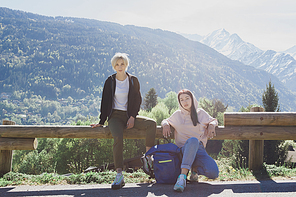 beautiful young female travelers  while resting on wooden fence in scenic mountains, mont blanc, alps