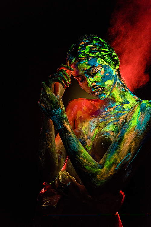 portrait of beautiful woman with colorful ultraviolet paints on body on black backdrop