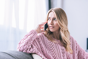 attractive blonde woman talking on smartphone at home